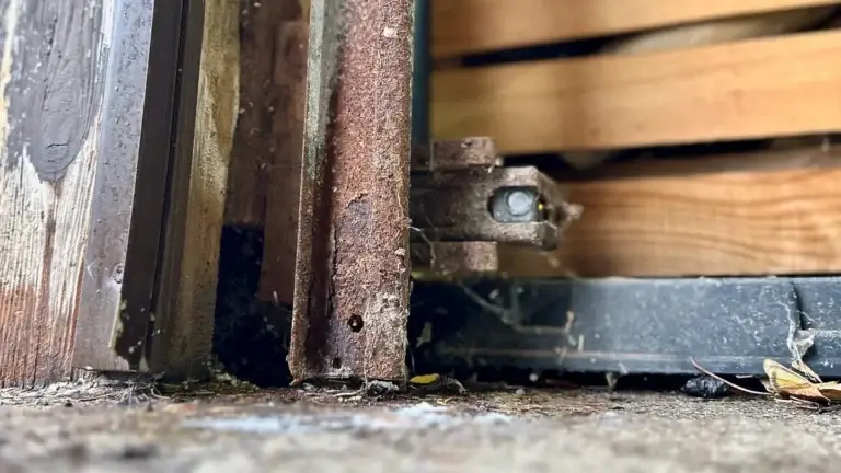 Heavily rusted garage door vertical track and bracket at the floor
